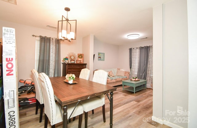 dining area with light hardwood / wood-style flooring and a chandelier