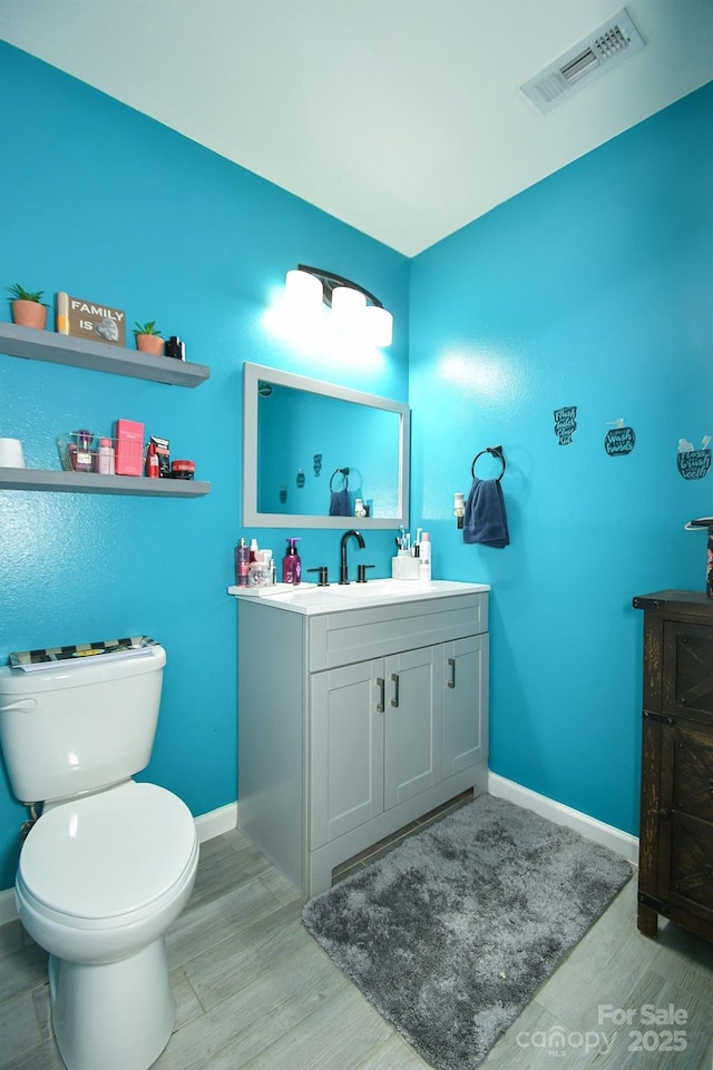 bathroom featuring toilet, vanity, and hardwood / wood-style flooring