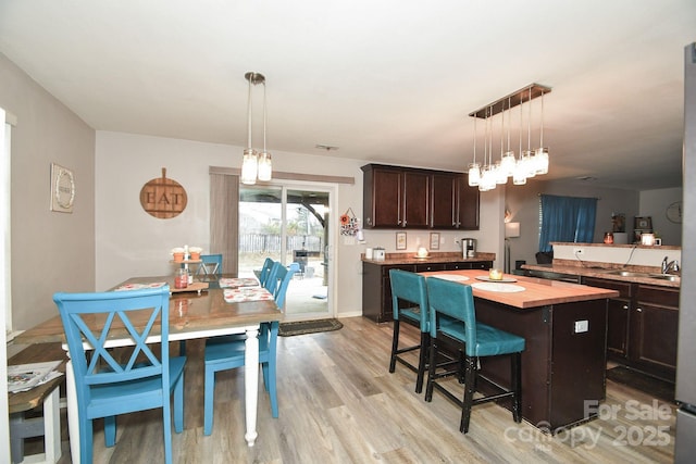 11677 Striker Ln, Midland, NC 28107 - kitchen featuring butcher block countertops, dark brown cabinetry, a center island, light wood-style floors, and a breakfast bar area