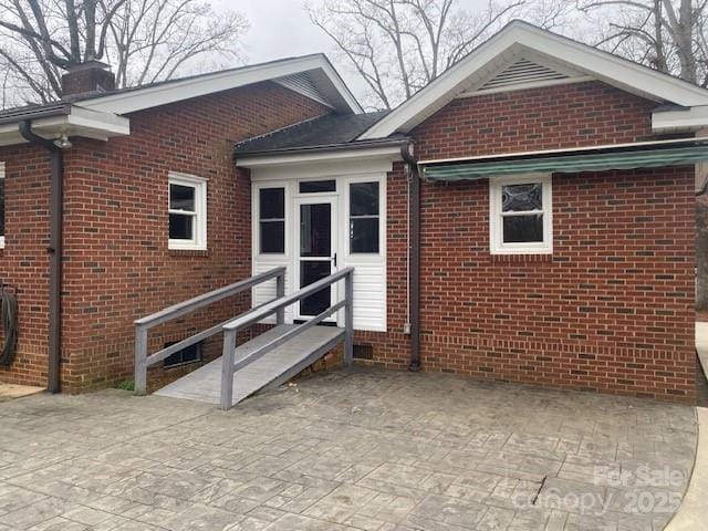 property entrance featuring brick siding and a chimney