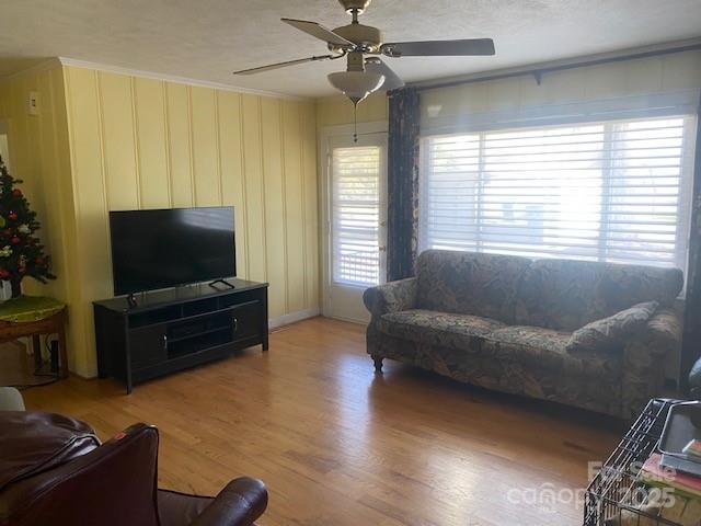 living room featuring ceiling fan, crown molding, and wood-type flooring