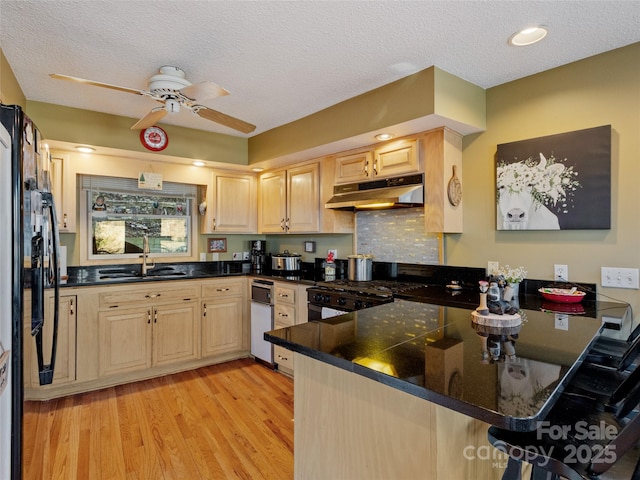 kitchen featuring light brown cabinets, sink, a textured ceiling, light hardwood / wood-style floors, and kitchen peninsula