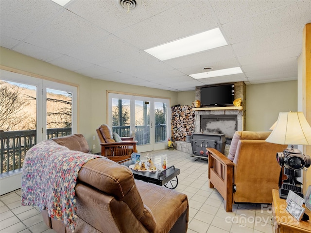 living room featuring a wealth of natural light, a drop ceiling, and light tile patterned flooring