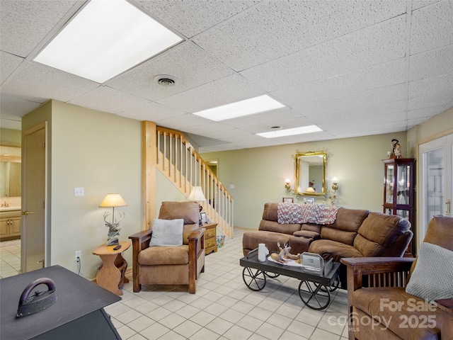 living room with light tile patterned floors, a paneled ceiling, and sink