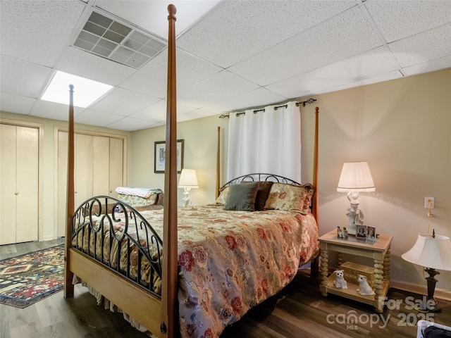 bedroom with a drop ceiling and dark hardwood / wood-style flooring