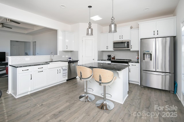 kitchen with appliances with stainless steel finishes, backsplash, sink, dark stone countertops, and white cabinets