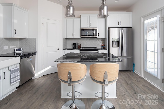 kitchen featuring decorative light fixtures, dark stone countertops, white cabinetry, and stainless steel appliances