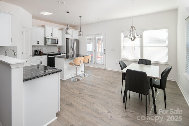 kitchen featuring white cabinets, hanging light fixtures, decorative backsplash, a kitchen island, and stainless steel appliances