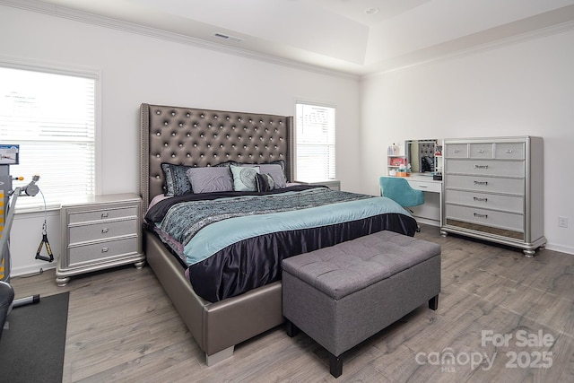 bedroom featuring wood-type flooring, a raised ceiling, and multiple windows