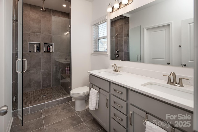 bathroom with toilet, vanity, tile patterned floors, and a shower with shower door