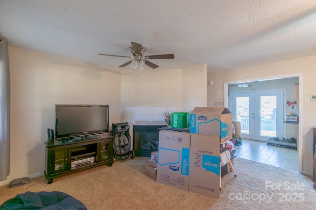 living room featuring ceiling fan, french doors, light colored carpet, and a textured ceiling