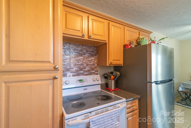 kitchen featuring tasteful backsplash, a textured ceiling, white electric stove, tile patterned flooring, and stainless steel refrigerator