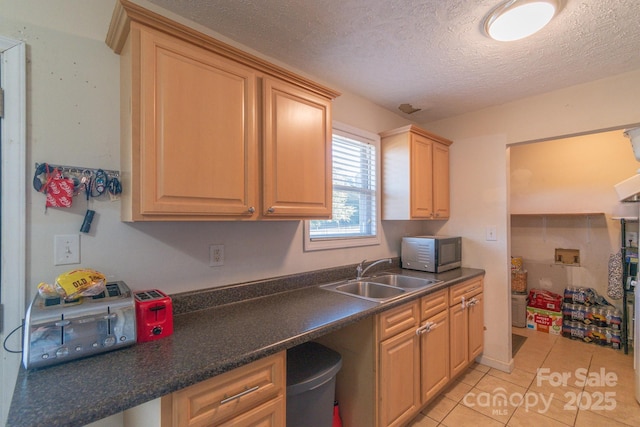 kitchen featuring a textured ceiling, light tile patterned floors, and sink