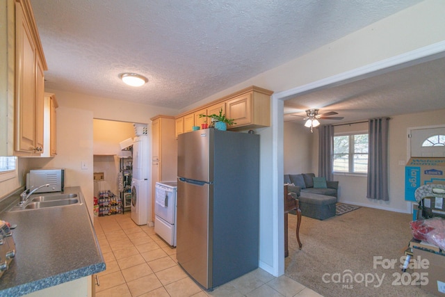 kitchen featuring light tile patterned floors, electric stove, light brown cabinetry, and stainless steel refrigerator