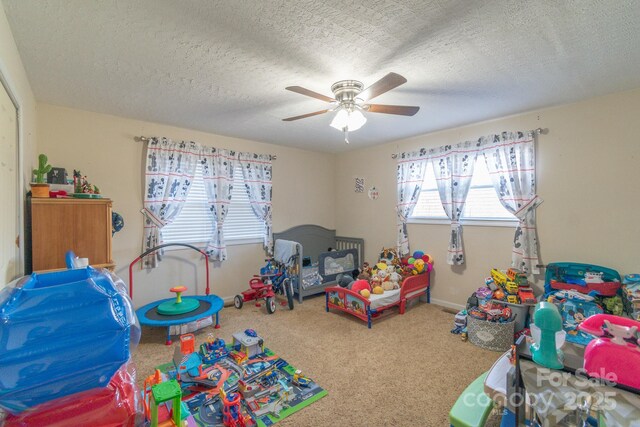 playroom with carpet flooring, ceiling fan, and a textured ceiling