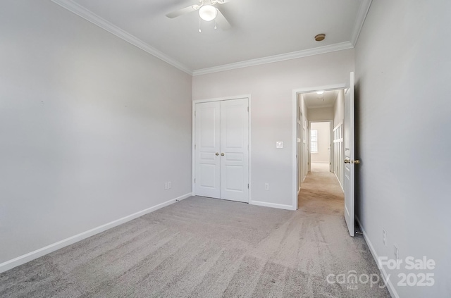 unfurnished bedroom featuring crown molding, ceiling fan, light colored carpet, and a closet