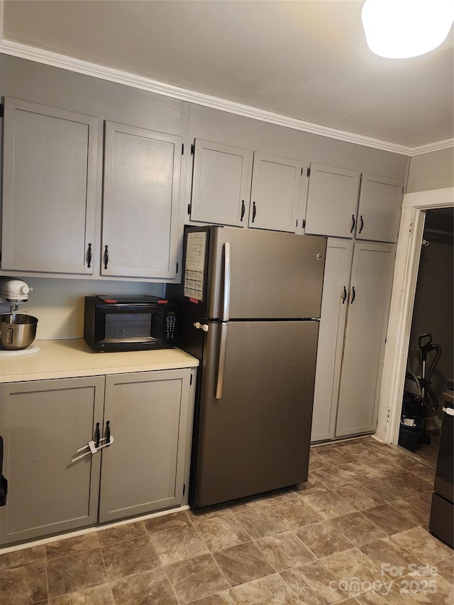 kitchen featuring stainless steel fridge, ornamental molding, and gray cabinetry