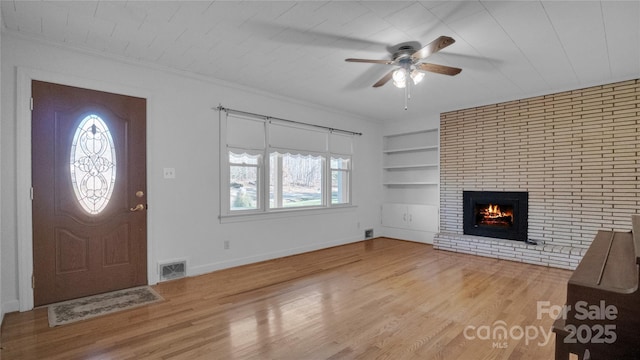 entrance foyer featuring a fireplace, light hardwood / wood-style flooring, ceiling fan, and ornamental molding