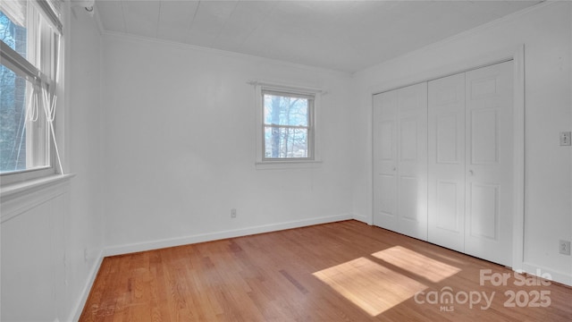 unfurnished bedroom featuring crown molding, a closet, and light wood-type flooring