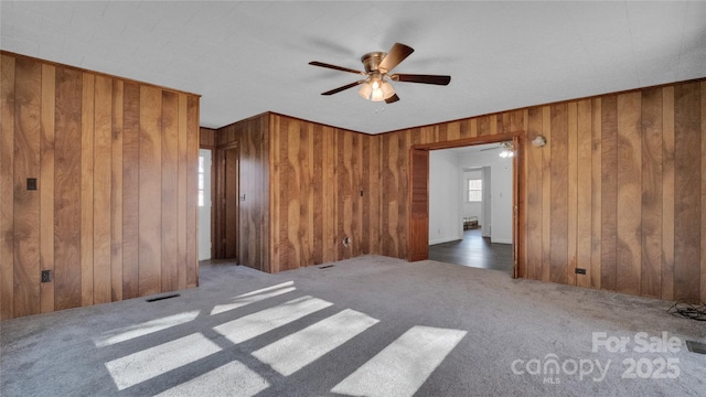 unfurnished room featuring wood walls and dark carpet