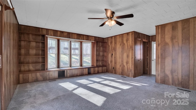 unfurnished room with ceiling fan, carpet floors, and wooden walls