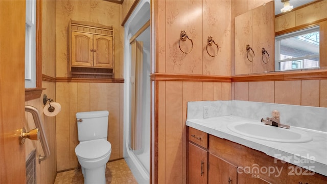 bathroom with vanity, toilet, an enclosed shower, and wooden walls