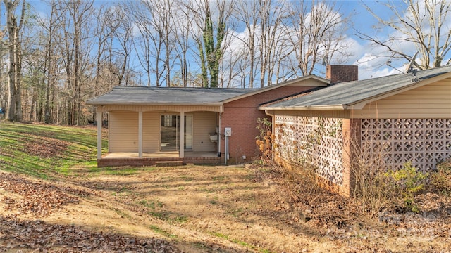 back of house featuring a lawn and covered porch