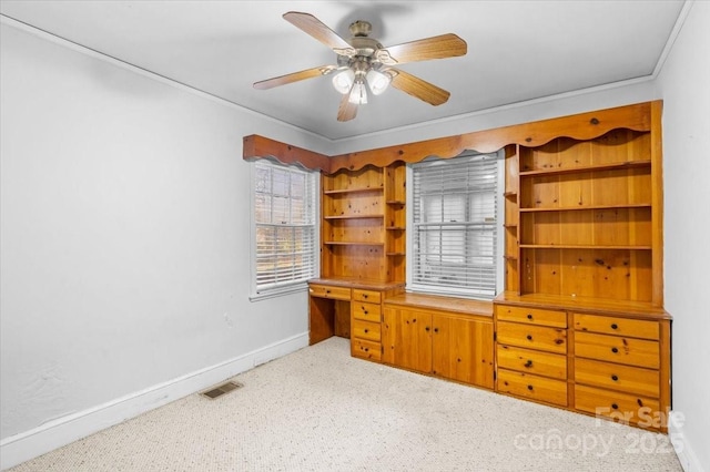 unfurnished office featuring ceiling fan, crown molding, and light colored carpet