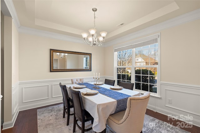 dining room with dark hardwood / wood-style floors, a tray ceiling, and a notable chandelier