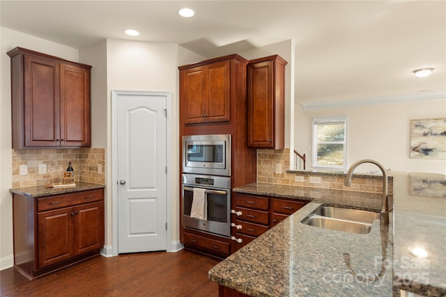 kitchen featuring dark hardwood / wood-style flooring, stainless steel appliances, dark stone counters, tasteful backsplash, and sink