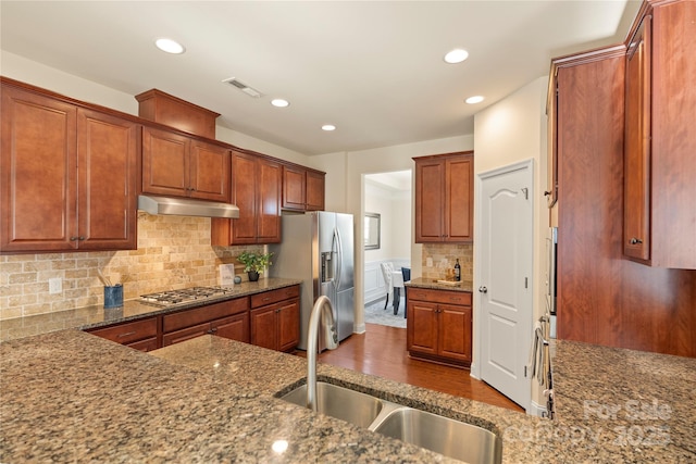 kitchen featuring sink, stone counters, stainless steel appliances, and tasteful backsplash