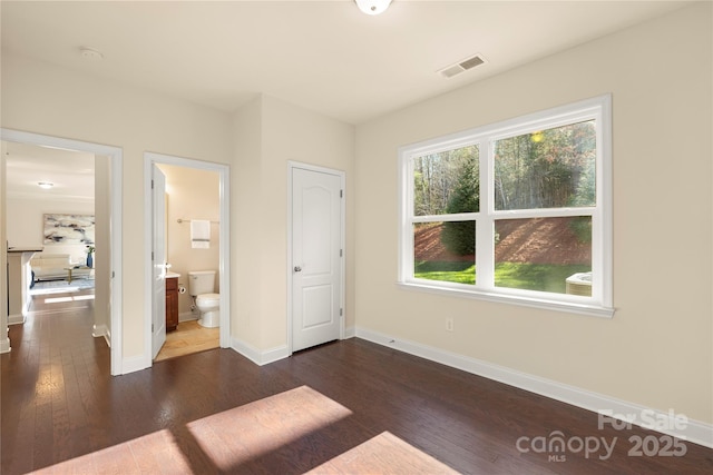 unfurnished bedroom with dark wood-type flooring and ensuite bath