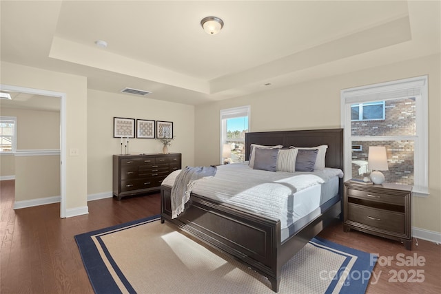 bedroom featuring dark hardwood / wood-style flooring and a raised ceiling