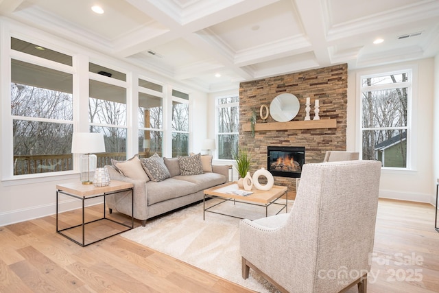 living room with a stone fireplace, beamed ceiling, coffered ceiling, light hardwood / wood-style floors, and crown molding