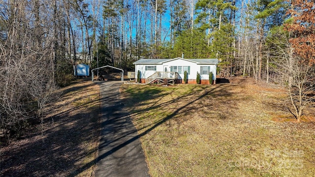 manufactured / mobile home featuring a storage shed, a front yard, and a carport