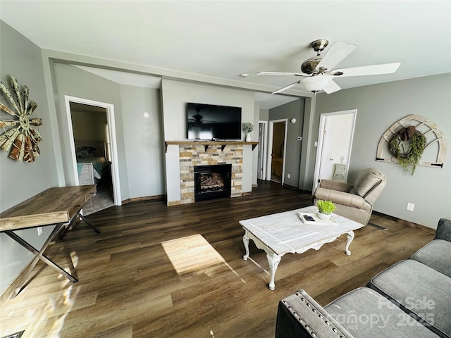 living room with a fireplace, ceiling fan, and dark wood-type flooring