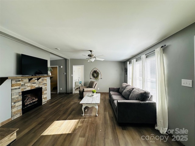 living room featuring dark hardwood / wood-style floors, a stone fireplace, and ceiling fan