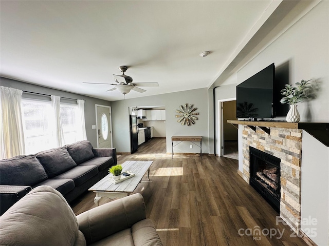 living room featuring dark hardwood / wood-style floors, a stone fireplace, and ceiling fan