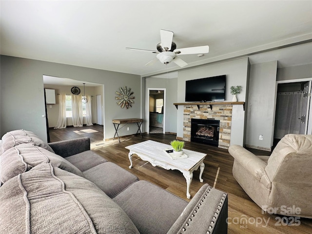 living room with ceiling fan, a fireplace, and dark wood-type flooring