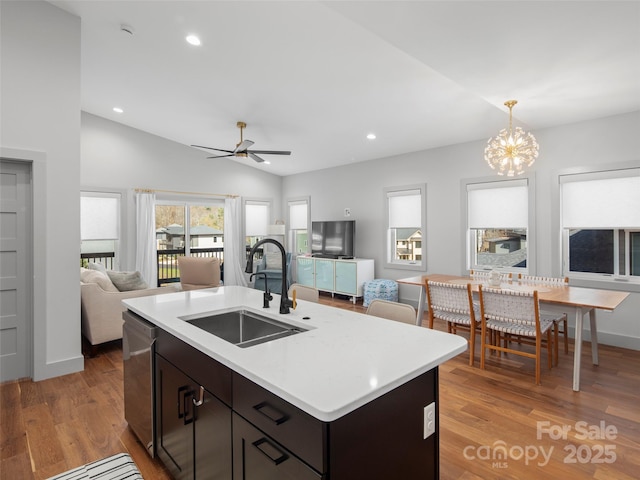 kitchen with ceiling fan with notable chandelier, sink, light hardwood / wood-style flooring, vaulted ceiling, and decorative light fixtures