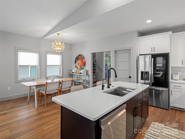 kitchen with a center island with sink, sink, hanging light fixtures, white cabinetry, and stainless steel appliances