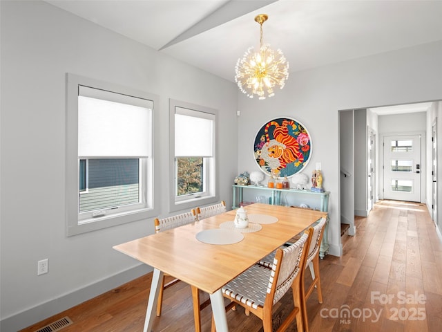 dining area featuring radiator, wood-type flooring, lofted ceiling, and an inviting chandelier