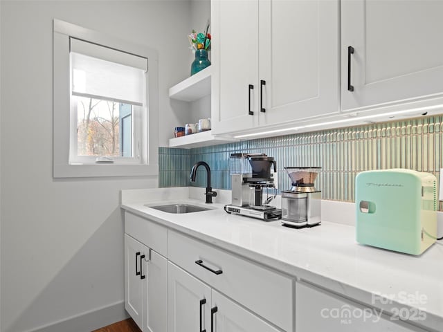 bar featuring light stone countertops, white cabinetry, and sink