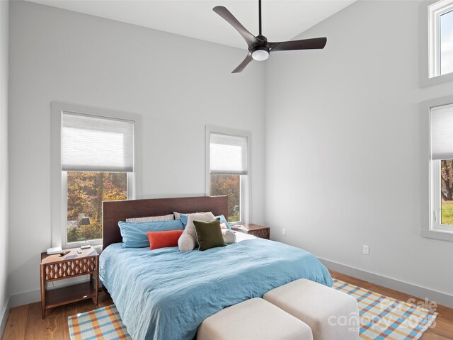 bedroom with ceiling fan, high vaulted ceiling, and wood-type flooring