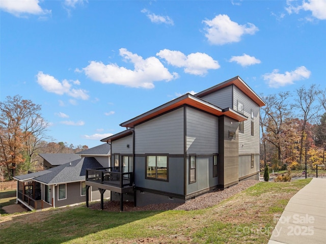 view of property exterior featuring a sunroom, a deck, and a yard