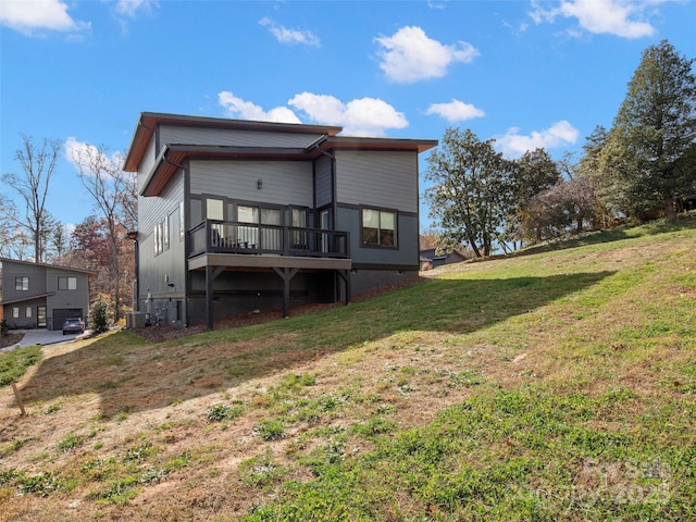 rear view of house with a lawn, a wooden deck, and central AC