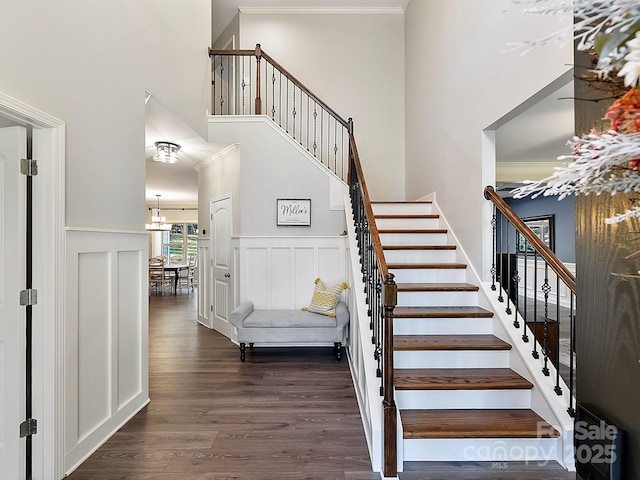 stairway with hardwood / wood-style flooring, a towering ceiling, and a chandelier