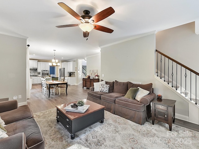 living room with hardwood / wood-style flooring, ceiling fan with notable chandelier, and ornamental molding