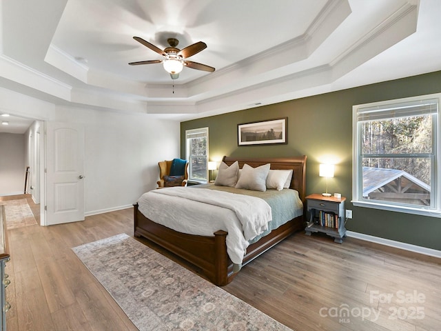 bedroom featuring a raised ceiling, ceiling fan, and wood-type flooring