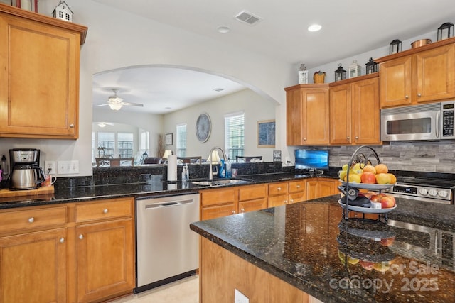 kitchen featuring ceiling fan, sink, dark stone counters, and appliances with stainless steel finishes